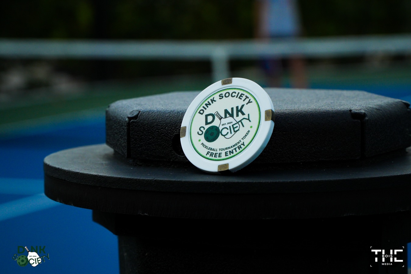 A Dink Society free-entry tournament token resting courtside